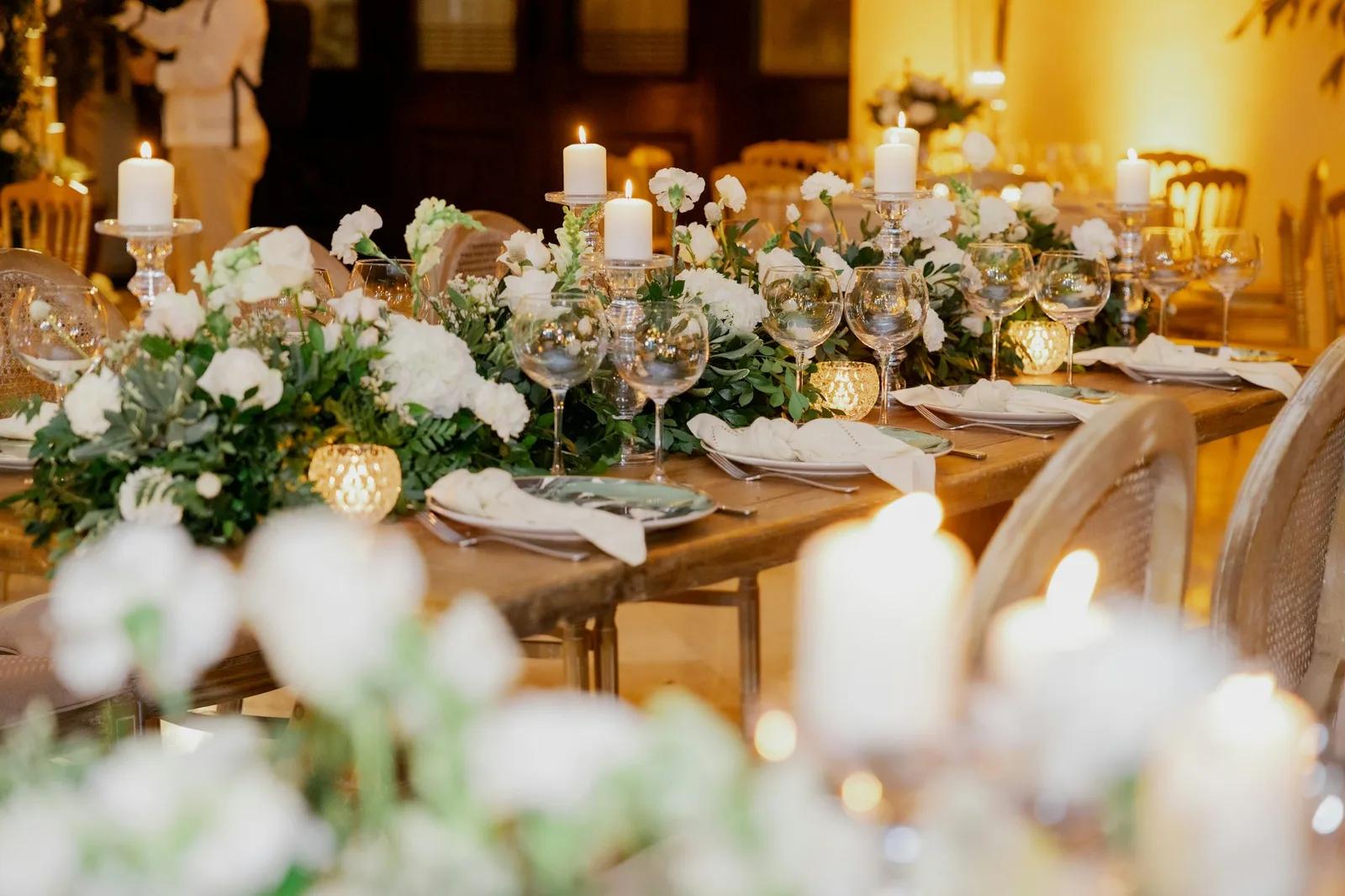 Une table de mariage aux chandelles, avec des fleurs blanches, des verres et des serviettes pliées