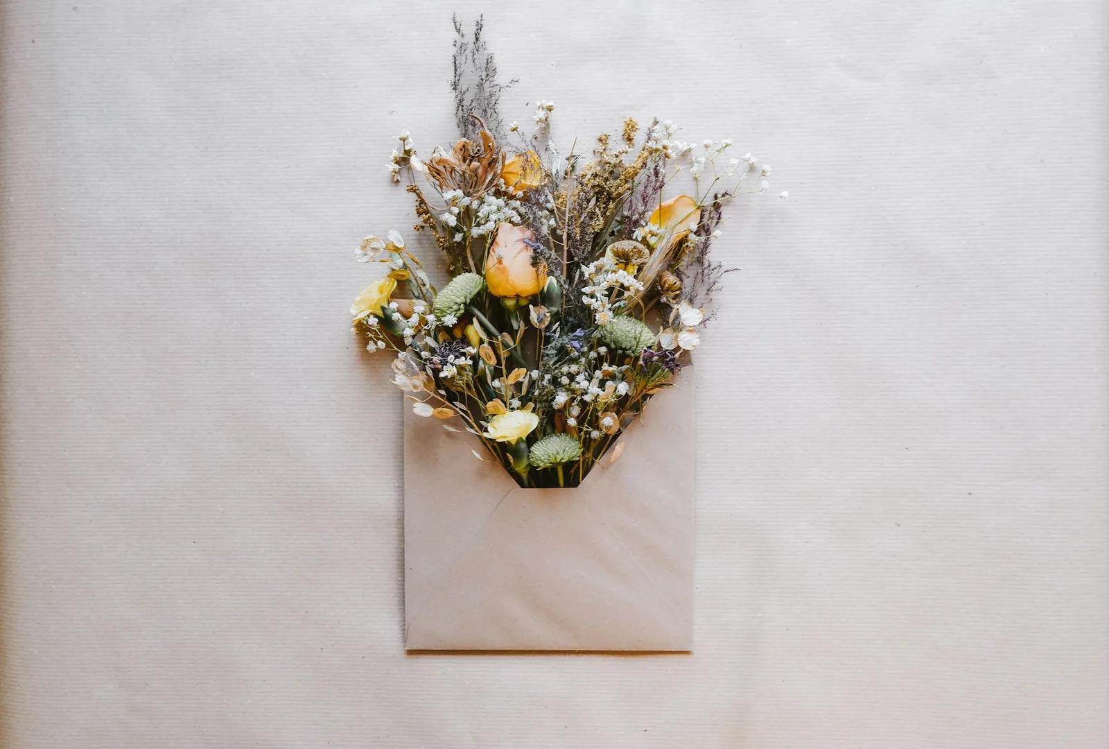 Un ramo de flores secas metido en un sobre de papel kraft
